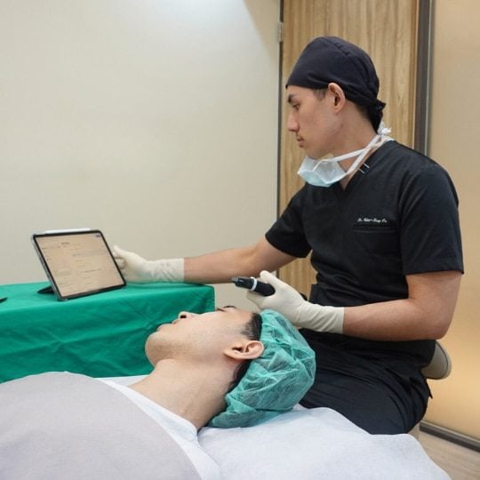 A doctor holding an ultrasound probe to scan and assess a patient's face